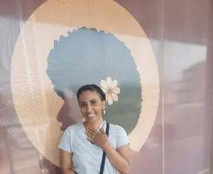 A woman standing in front of a mural with a flower on it.