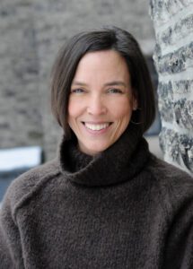 Smiling woman in brown turtleneck sweater.