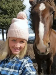 Woman in hat smiling next to horse.