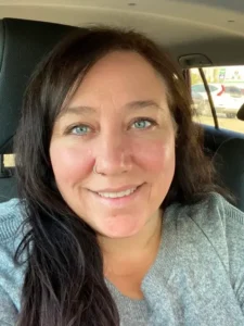 Woman with long dark hair smiling in a car.