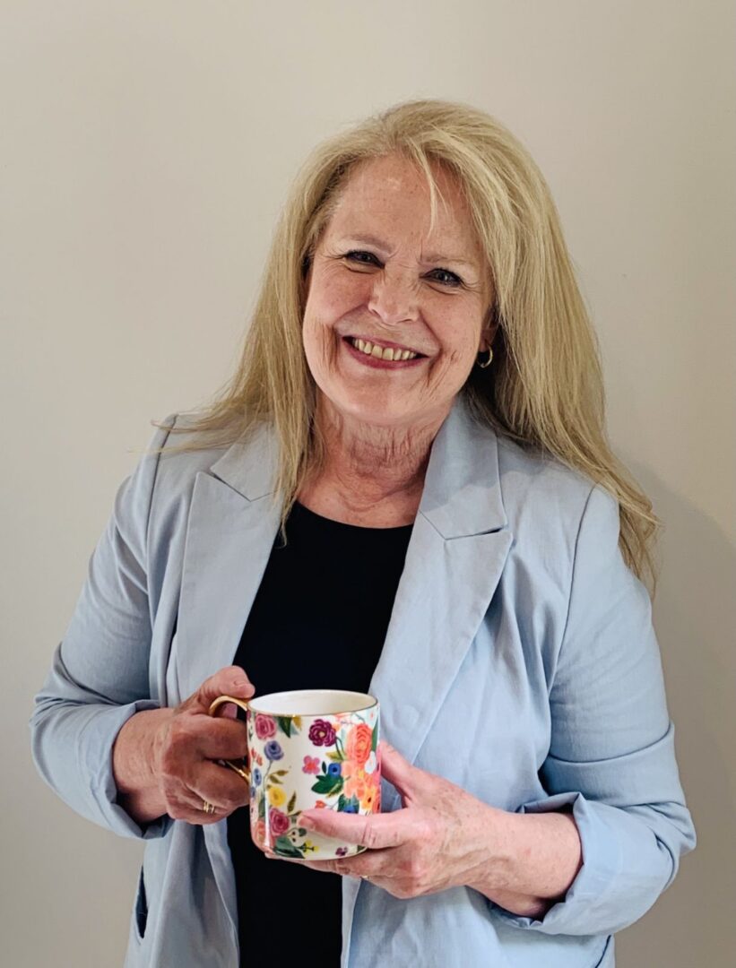 Smiling woman holding a floral mug.