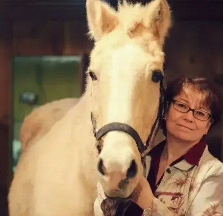 A woman petting a white horse.