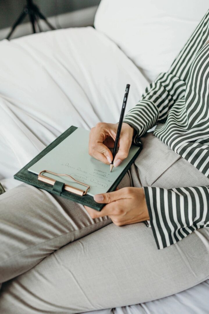 Person writing on a clipboard in bed.