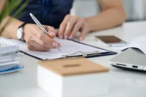 Woman signing paperwork at a desk.