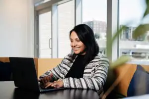 Woman smiling while working on laptop.