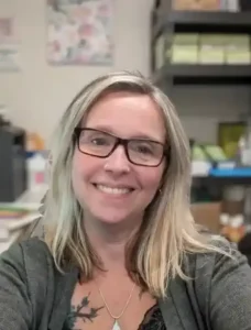 Smiling woman with glasses and necklace.