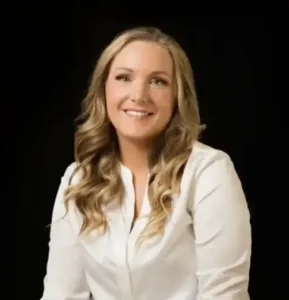 Woman with long blonde hair smiling in white shirt.