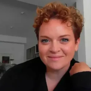 Woman with curly hair smiling at camera.