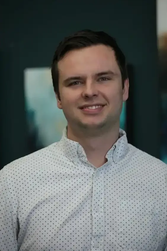 Smiling man in a white polka dot shirt.