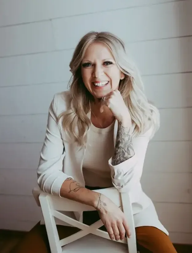 Smiling woman with a tattoo sitting on a chair.