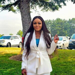 Woman in white suit outdoors, near cars.