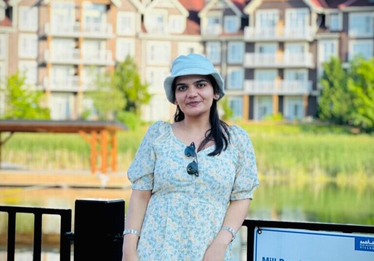 AKASH KAUR 2025 Woman wearing hat, floral dress, and sunglasses.