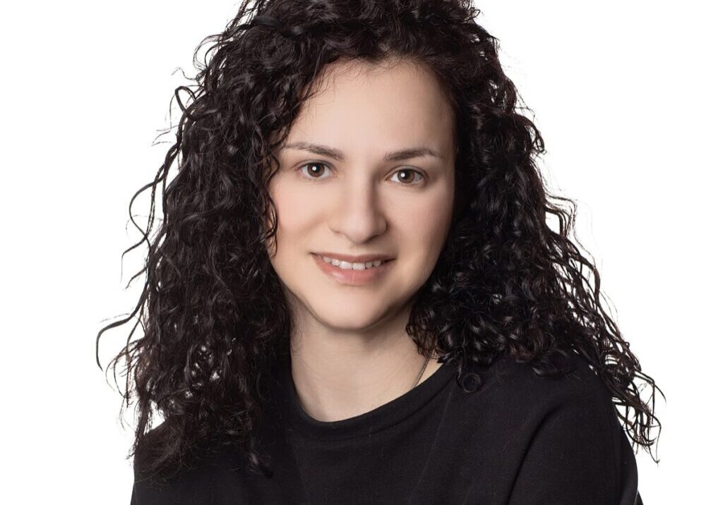 Anna Woman with curly hair smiling at camera.