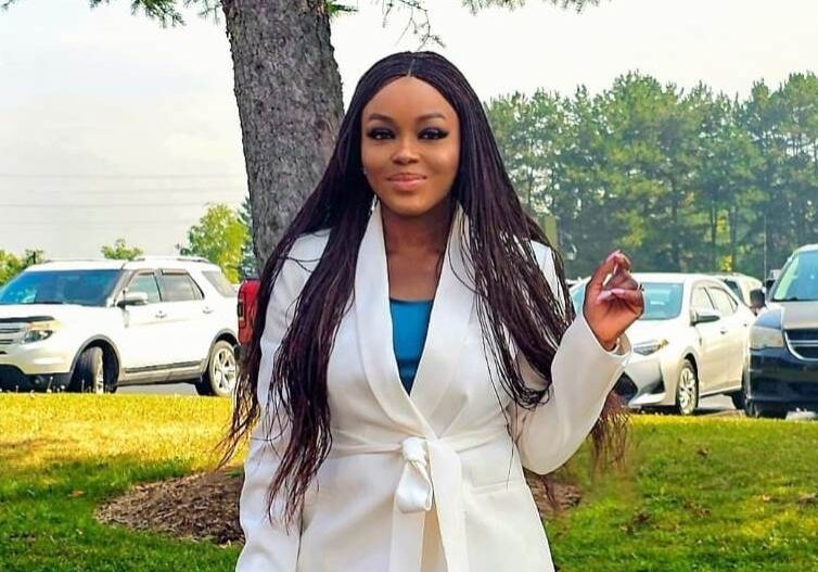 Woman in white suit outdoors, near cars.