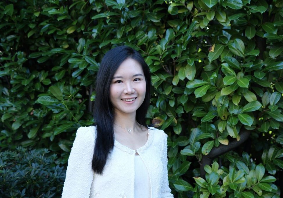 Cathy Feng 2025 Smiling woman standing in front of greenery.