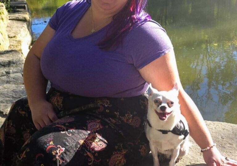 Woman with purple hair and a white dog.