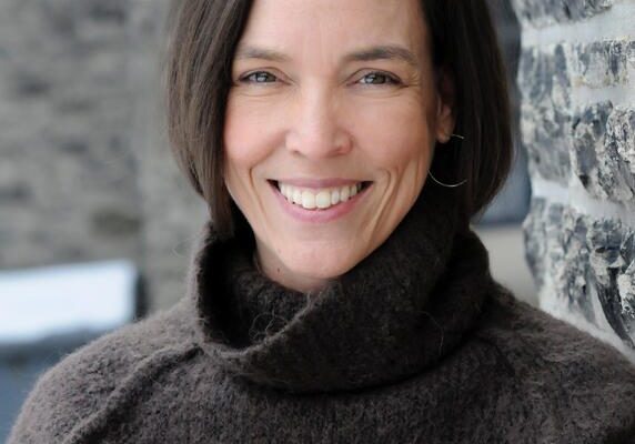 Smiling woman in brown turtleneck sweater.