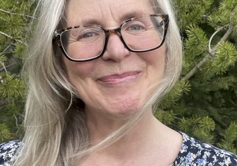 Hope 2025 Smiling woman with glasses in nature setting.