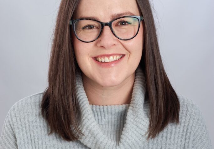 Megan 2024 Smiling woman wearing glasses and sweater.