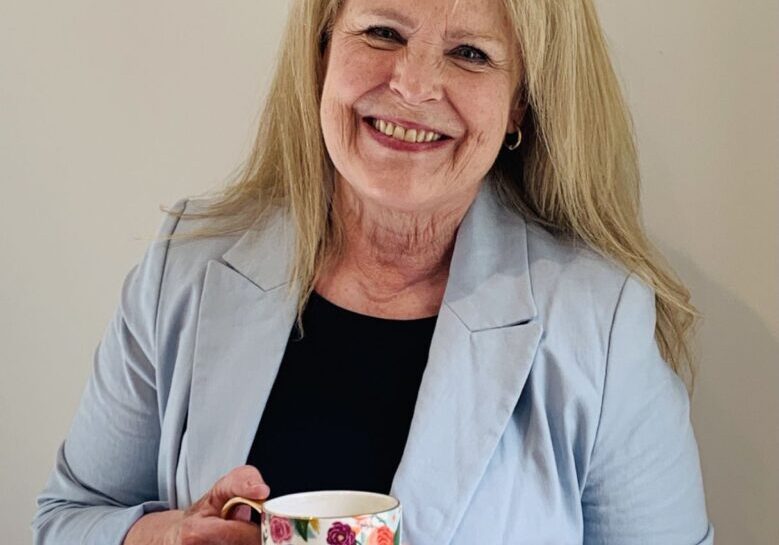 Michelle s Smiling woman holding a floral mug.