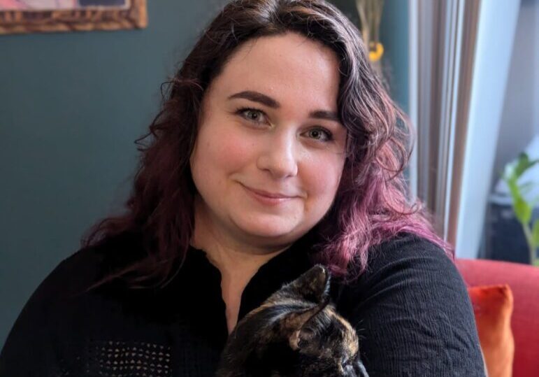 Person holding a cat, smiling indoors.