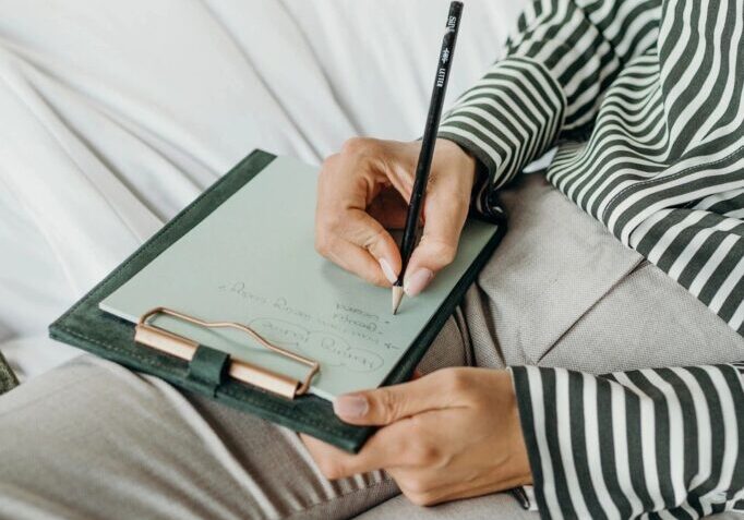 Person writing on a clipboard in bed.