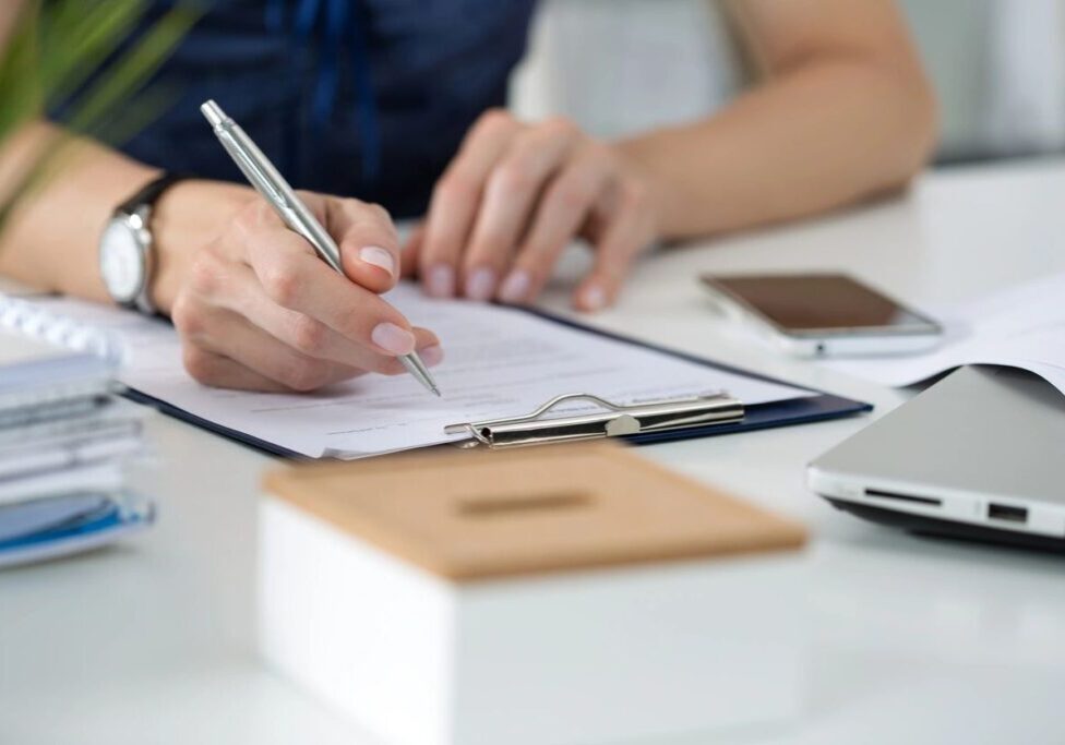qtq80-lKLg0I Woman signing paperwork at a desk.
