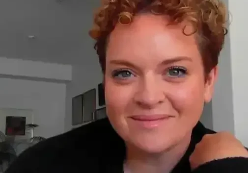 Woman with curly hair smiling at camera.