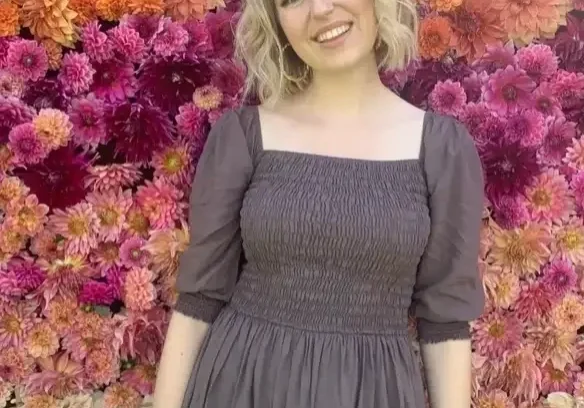 qt=q_74 (2) (1) Woman in a grey dress in front of flowers.