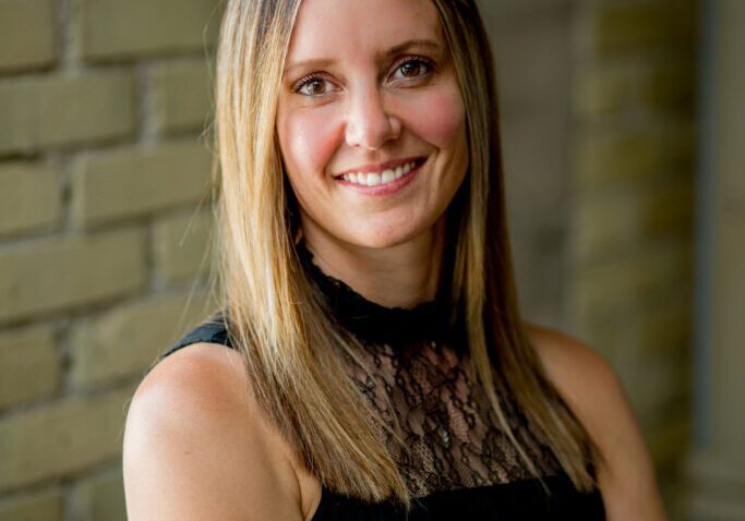 sarahtw-7 2024 Woman smiling with arms crossed, wearing black top.